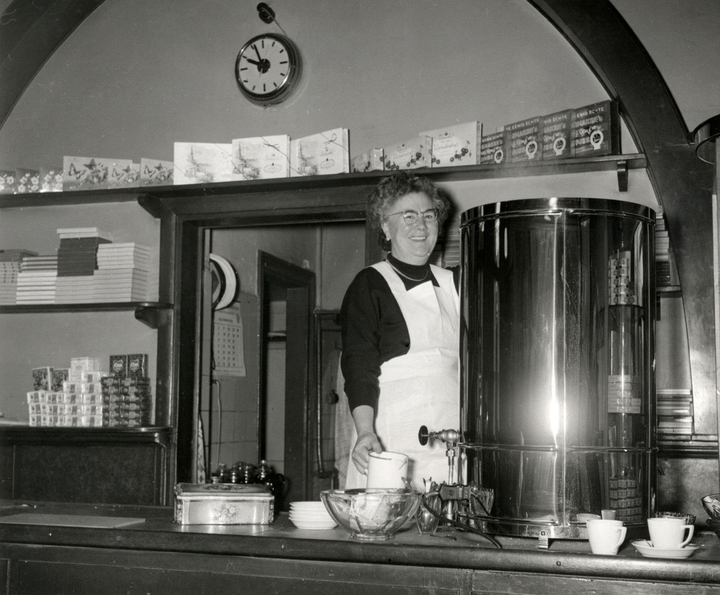 Mevrouw Baltus achter het buffet met de koffieketel in de stationsrestauratie op station Driebergen-Zeist, 1956.